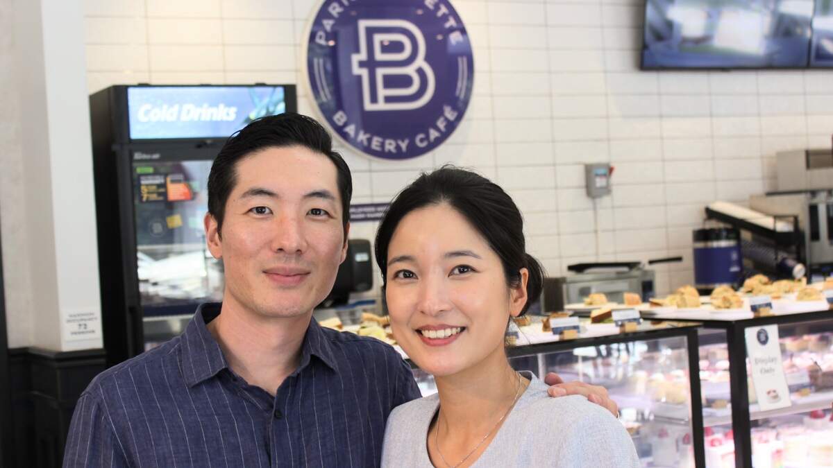 Chris, left, and Kim Shin, right, pose in their café during friends and family day on Aug. 18, 2026.